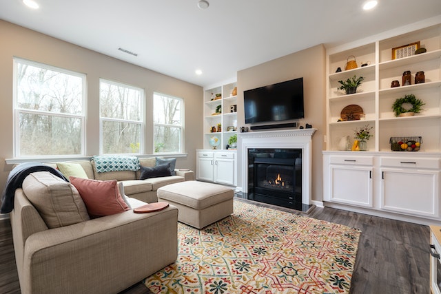 living room with three windows a white book shelf and a linen couch