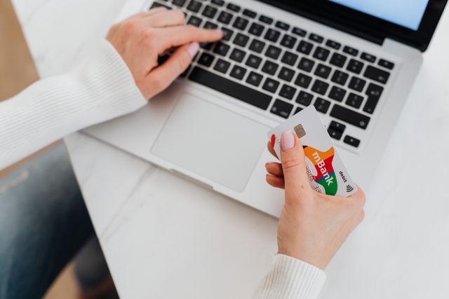 person on a laptop holding a bank card