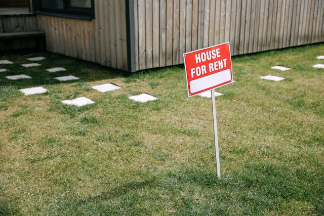 A house for rent sign stuck in the grass
