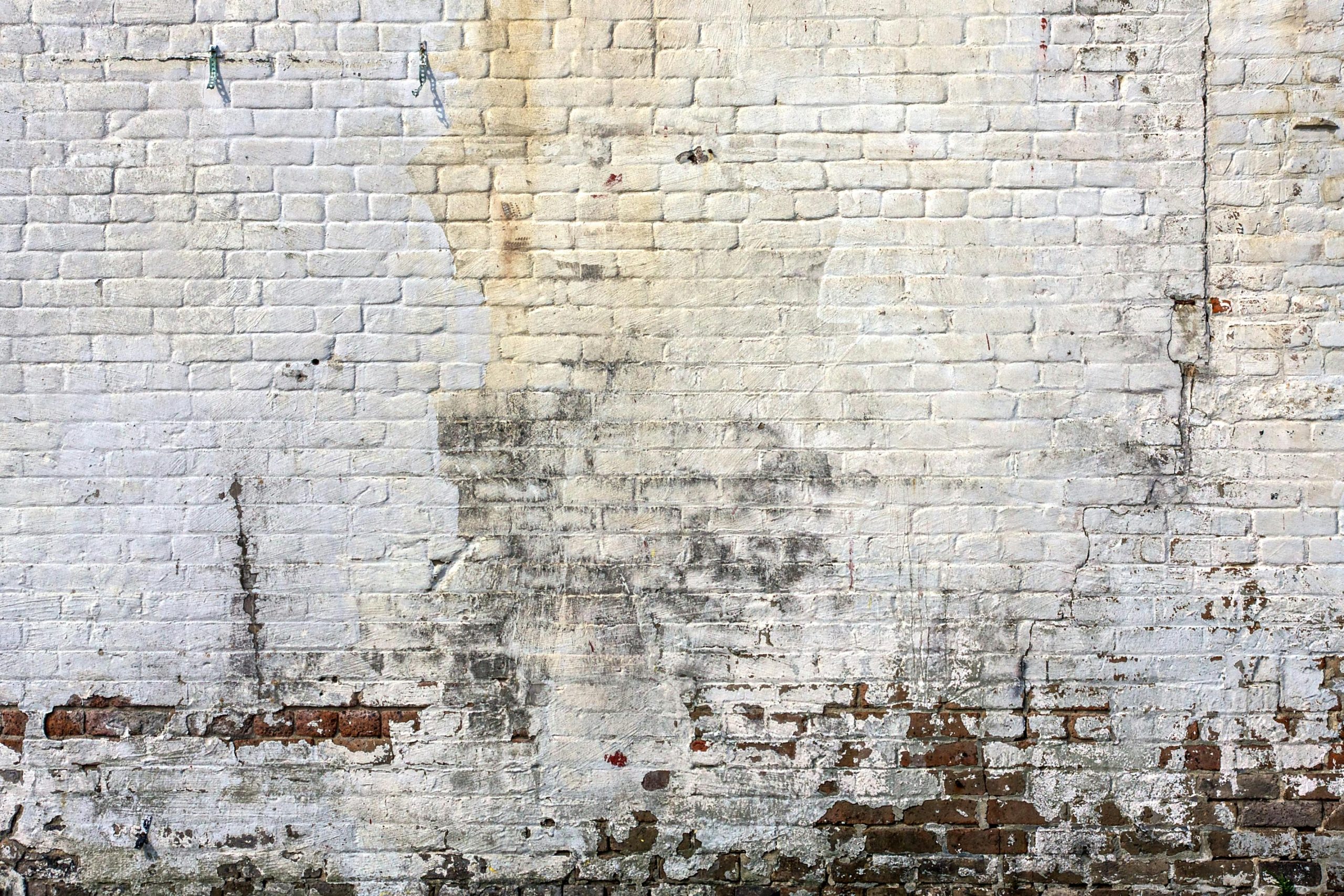 Worn-out brick wall with peeling paint.