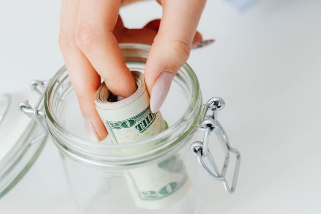 person putting money in a jar