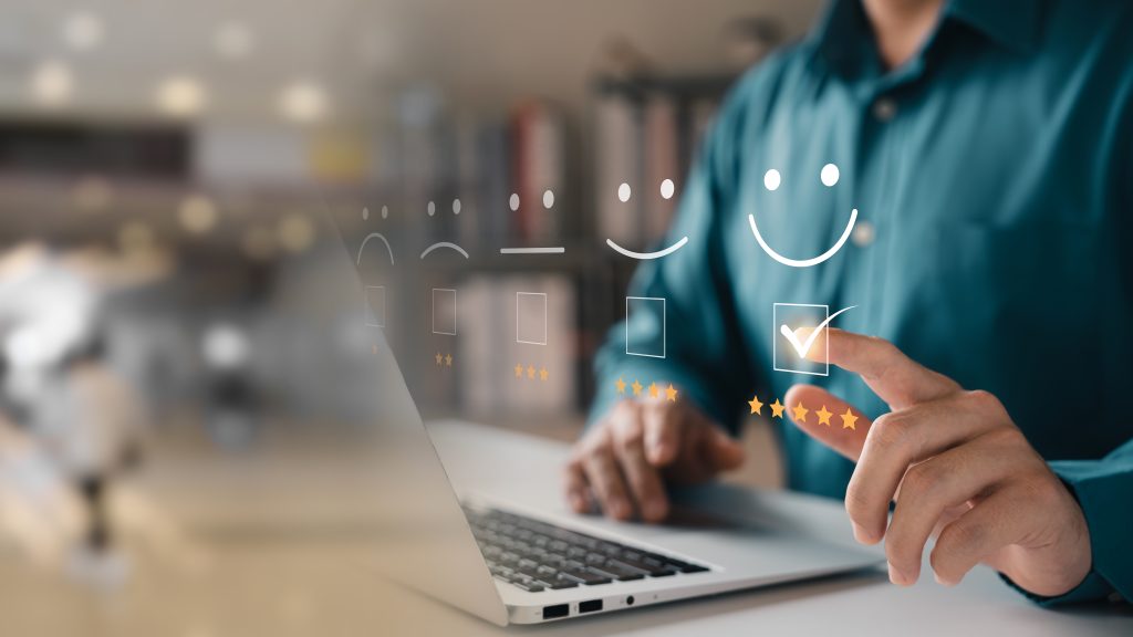 a person using a laptop, selecting a 5-star satisfaction rating with smiley faces