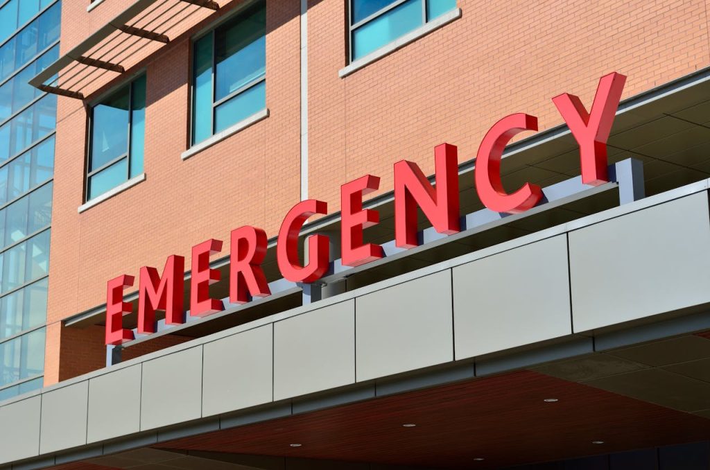 a red "emergency" sign over a hospital entrance