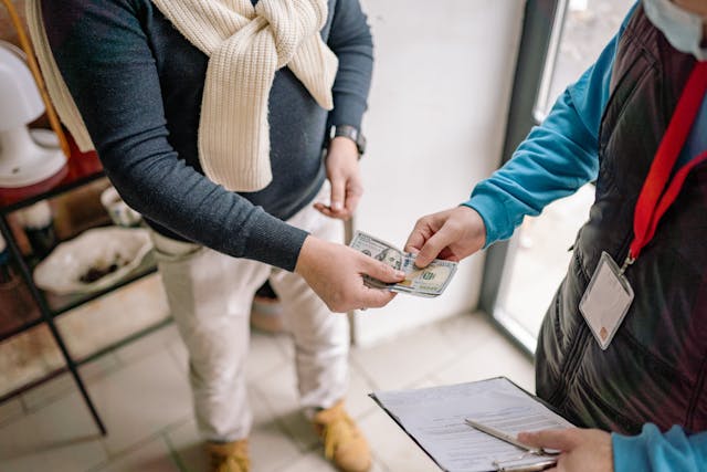 A person holding a clipboard handing another person money