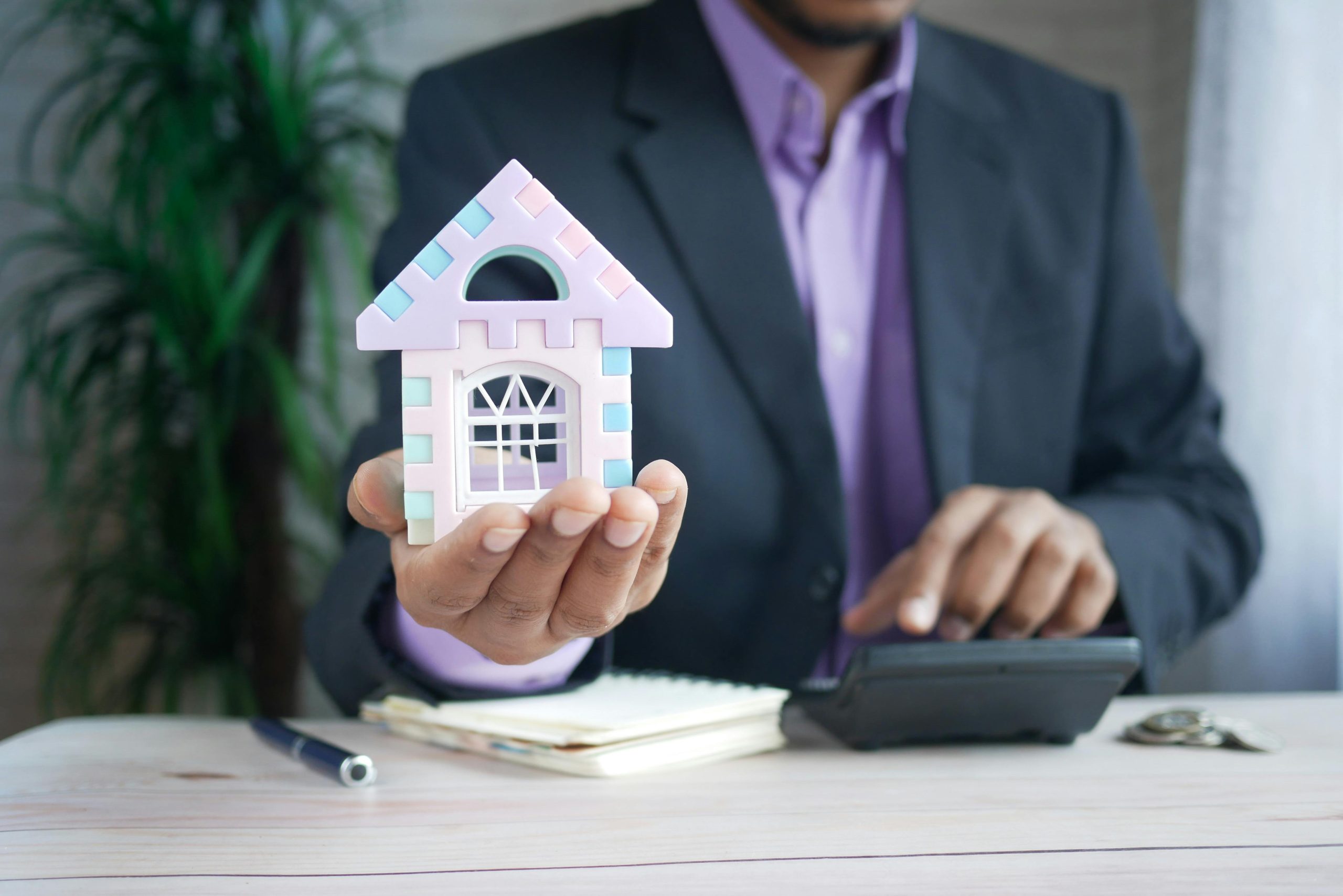 man holding a house and a calculator 