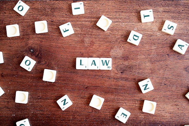 Scrabble tiles spread out while three in the middle spell "law"