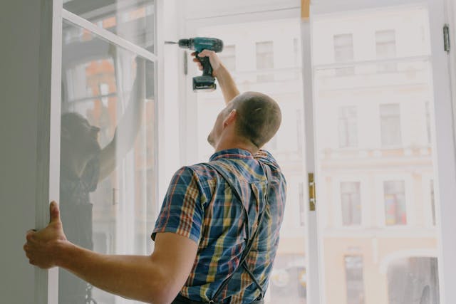 person drilling into a window sill